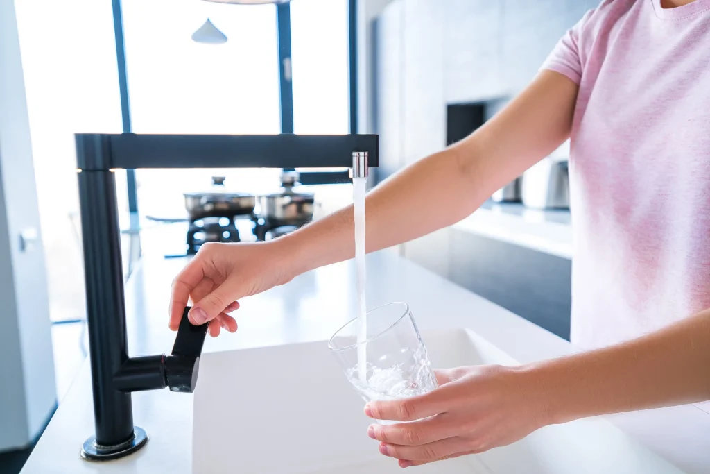 woman pours fresh filtered purified-water-drinking-from-faucet into glass kitchen home